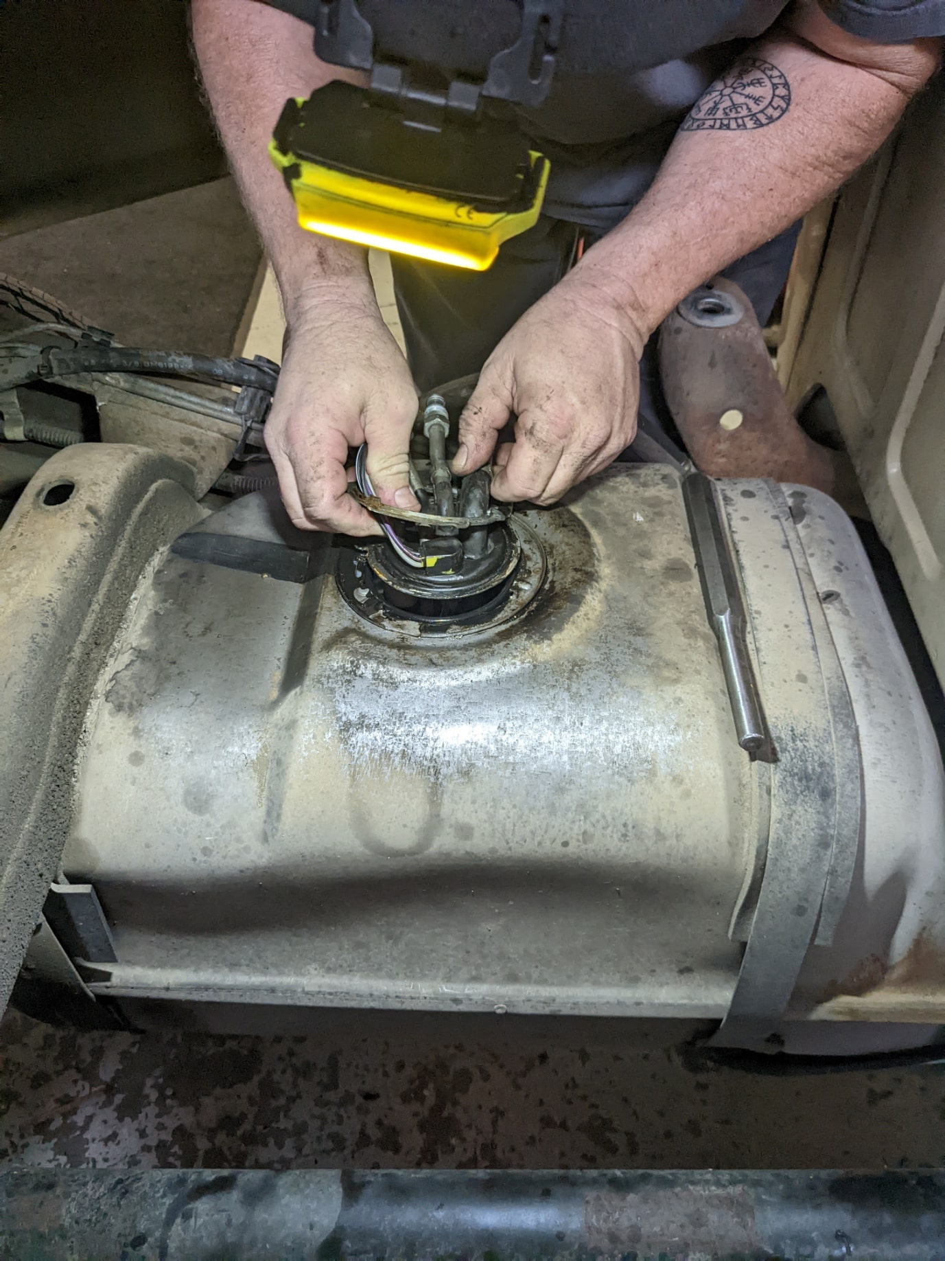 Technician repairing a vehicle's fuel tank with tools at Auburn Service Center.
