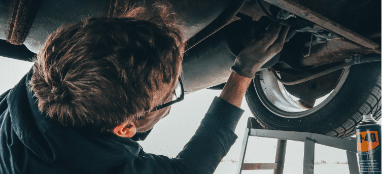 Auto repair technician inspecting vehicle undercarriage at Auburn Service Center.