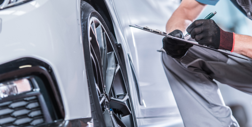 Car maintenance technician inspecting a vehicle's wheel and tire.
