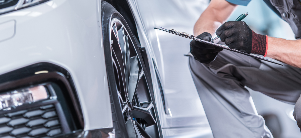 Car maintenance technician inspecting a vehicle's wheel and tire.