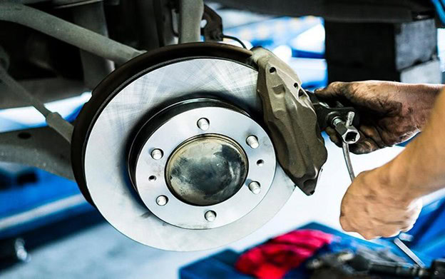 Car brake disc and caliper being inspected for signs of wear and damage.