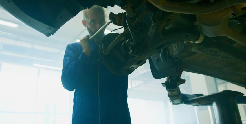 Technician inspecting vehicle transmission system under the car.