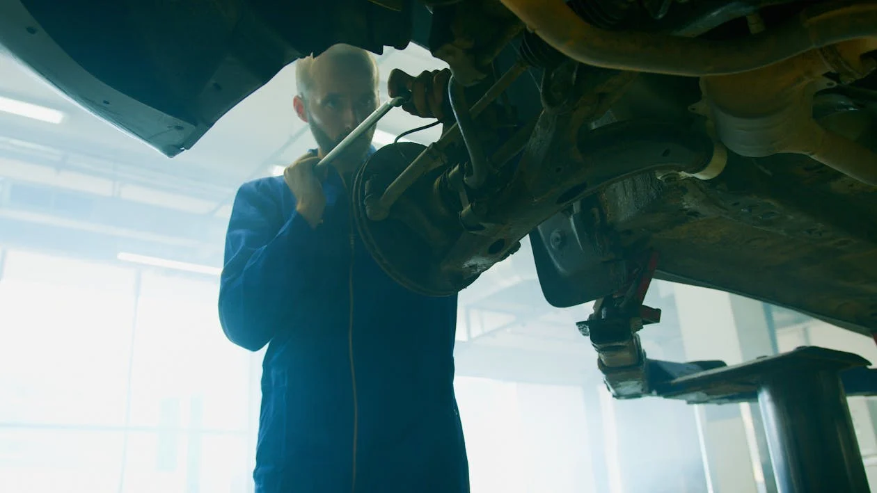 Technician inspecting vehicle transmission system under the car.