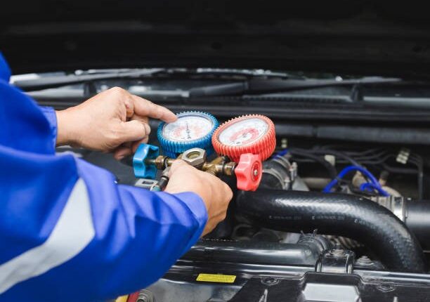 Technician performing a vehicle tune-up with gauges under the hood.