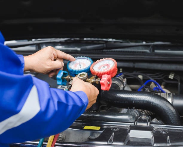 Technician performing a vehicle tune-up with gauges under the hood.