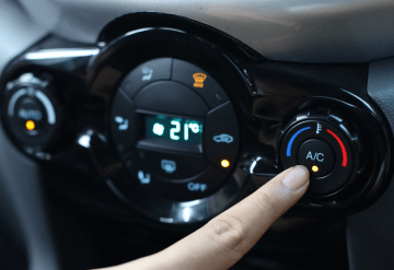 Car air conditioning control panel with a finger adjusting temperature settings.