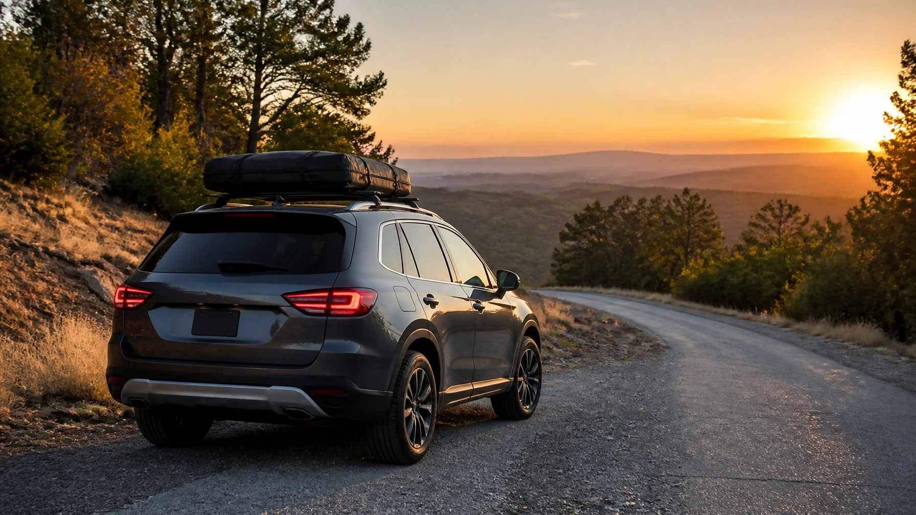 Black SUV parked on mountain road during sunset with scenic view.