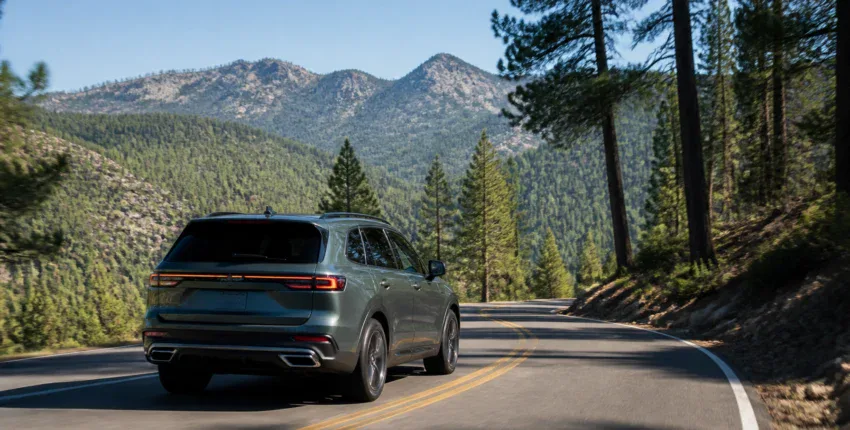 SUV driving on mountain road surrounded by pine trees and mountains.