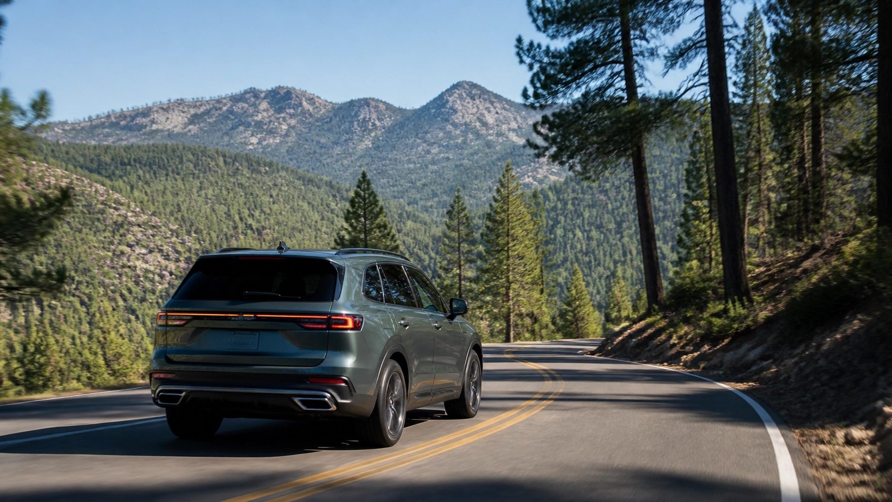 SUV driving on mountain road surrounded by pine trees and mountains.