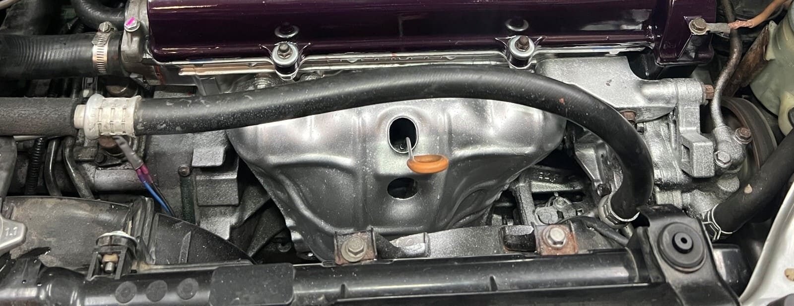Engine bay of a vehicle showing engine components at Authentic Automotive Repair.
