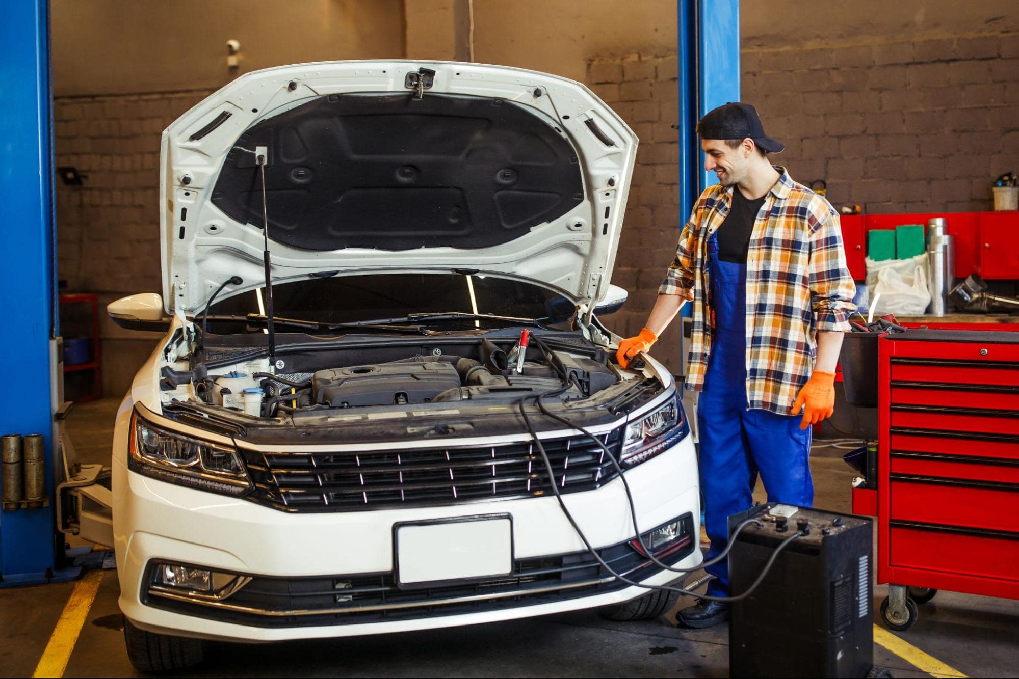 Auto mechanic testing car engine with diagnostic tools at repair shop.