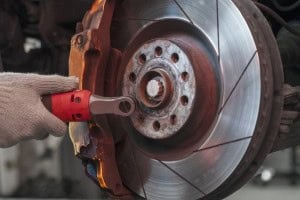 Close-up of a mechanic inspecting a car brake rotor with a diagnostic tool.
