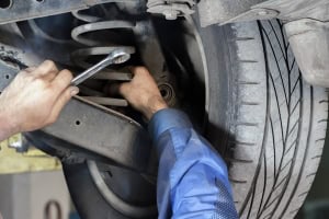 Auto repair technician working on a vehicle's suspension system.