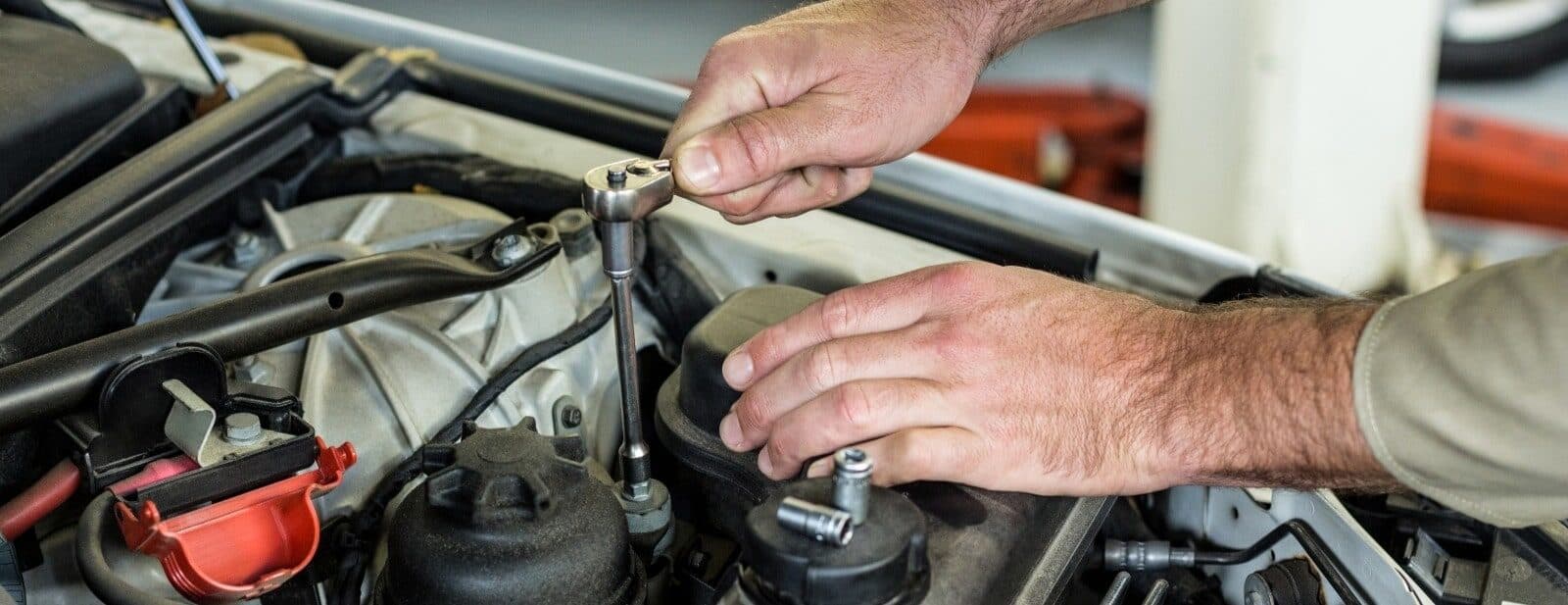 Auto repair technician inspecting car engine.