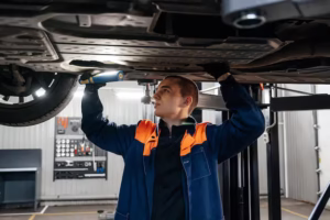 mechanic-blue-uniforms-inspecting-underside-car-with-flashlight-clipboard-symbolizing-teamwork-professional-service-quality-automotive-repair