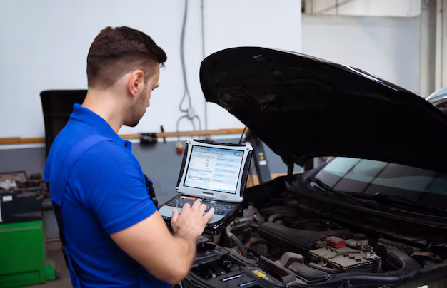 Automotive technician connecting a computer to a car for diagnostics in a workshop