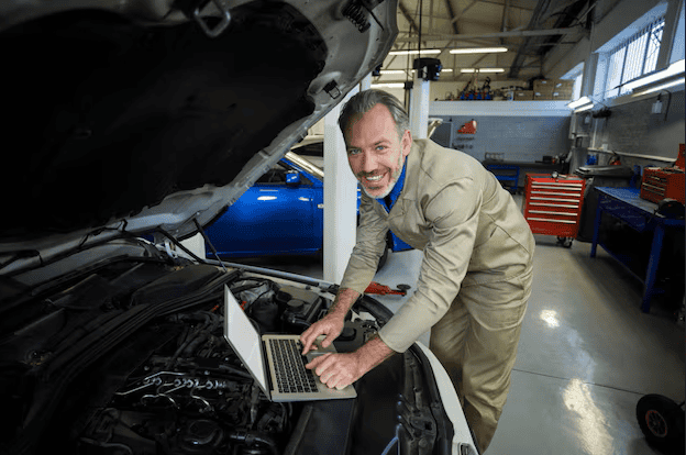 Auto technician performing diagnostics on a late-model vehicle with advanced tools.