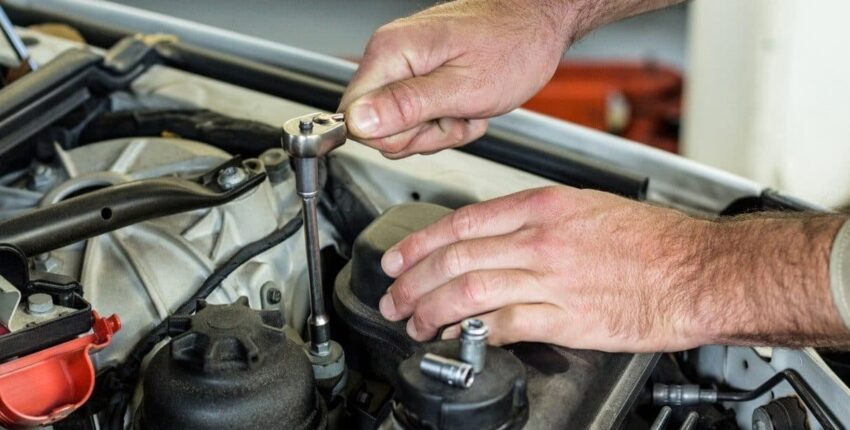 Mechanic performing car engine maintenance at Autocenters.
