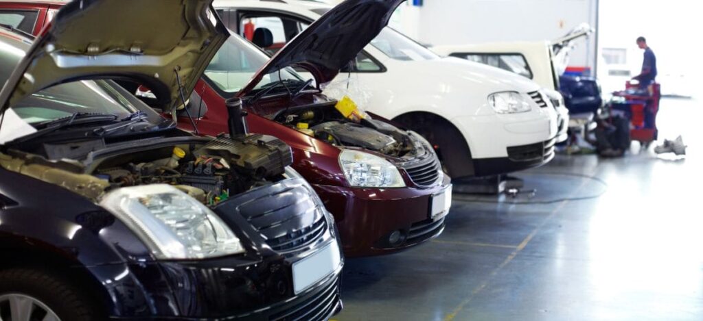 Modern car repair shop with multiple vehicles being serviced and inspected.