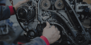 Skilled technician repairing car engine with tools at Autosauce Performance.