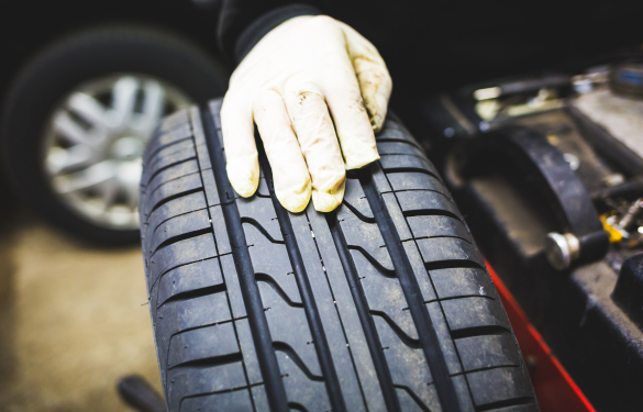 Technician performing wheel alignment on vehicle tire at Autosauce Performance.