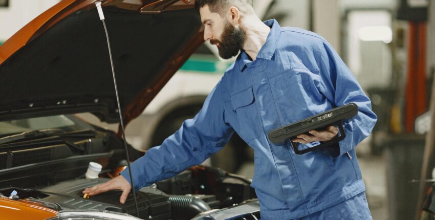Skilled mechanic inspecting car engine in auto repair shop.