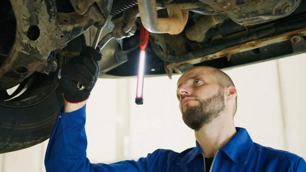 Skilled mechanic inspecting undercarriage of vehicle for repairs.