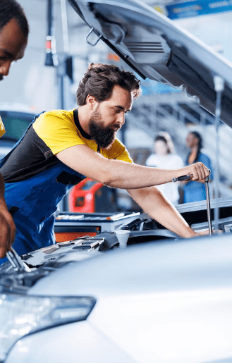Skilled mechanic inspecting engine bay of a modern car at Autosauce Performance.