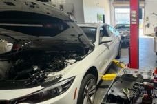 Professional car repair service at Auto Tech Solutions with a mechanic working on a white vehicle.