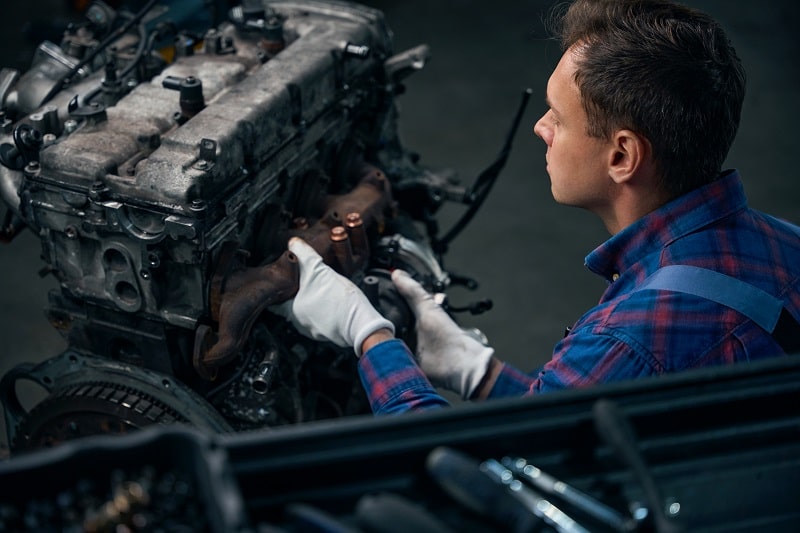 Skilled mechanic inspecting car engine during repair at Auto Tech Solutions.