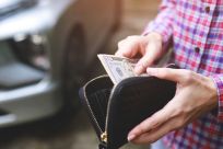 Person paying with cash at Auto Tech Solutions service center.