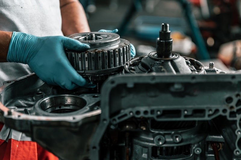 Technician inspecting car engine components during repair service.