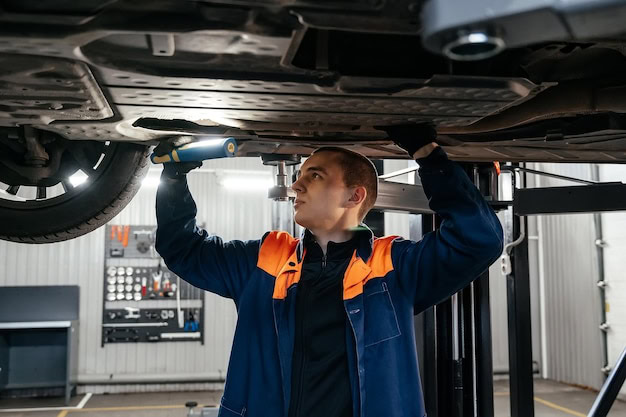 Auto Tech Solutions technician inspecting under a vehicle for sensor issues and diagnostics.