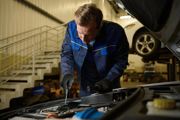 Auto technician inspecting engine during vehicle maintenance.