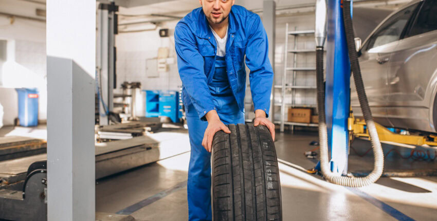 Auto mechanic inspecting a car tire in a professional auto repair shop.