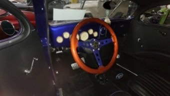 Vintage race car interior with classic steering wheel and dashboard.
