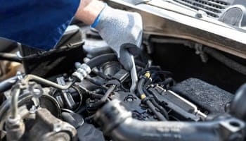 Skilled mechanic inspecting car engine for repairs at BC Automotive.
