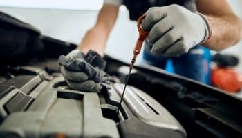 Technician performing engine oil change in a professional auto repair shop.