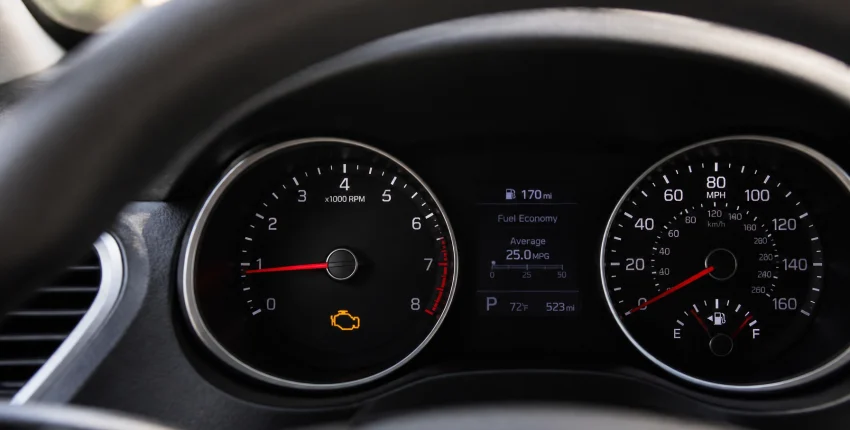 Car dashboard showing speed, fuel, and check engine light at Best Buy Auto Service.