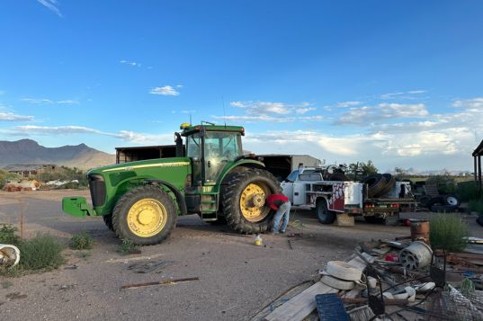 Agricultural tires on tractor with repair technician working on them.