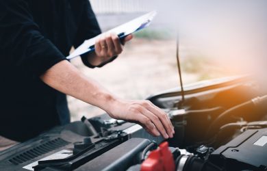Auto repair technician checking engine diagnostics under the hood.