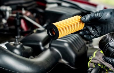Technician replacing oil filter during vehicle engine maintenance.
