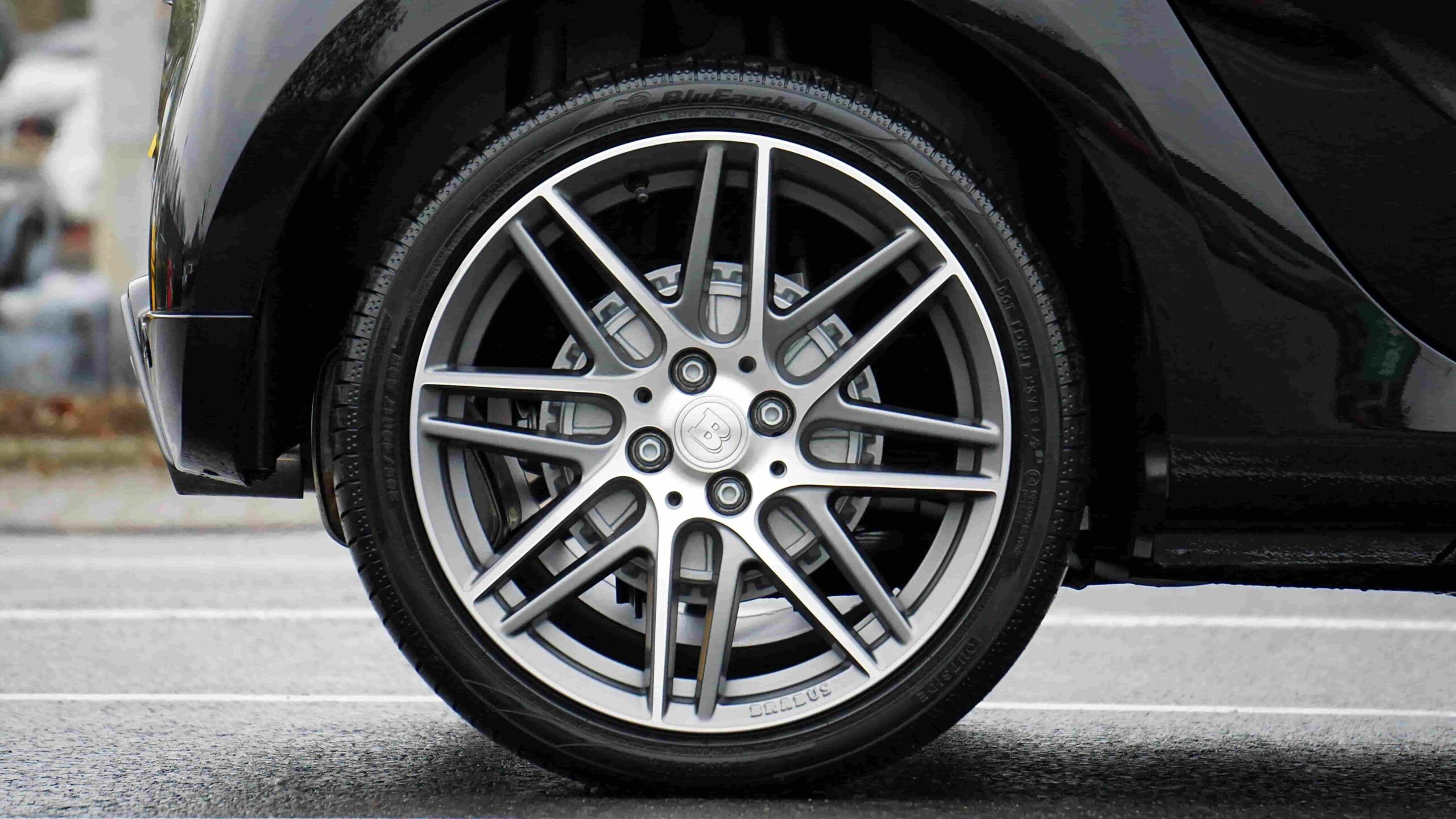 Close-up of a car tire showing tread wear and wheel details.