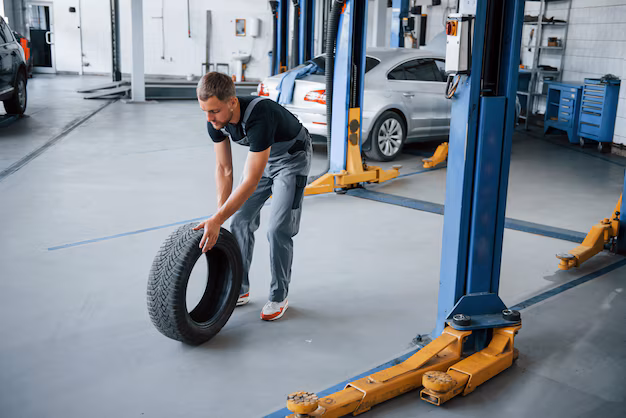 Mechanic rolling a car tire in an auto workshop