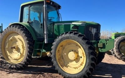 Green tractor on a farm with clear blue sky in the background.