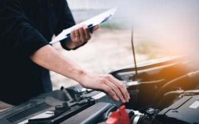 Technician inspecting car engine during maintenance service at Big Sky Tire.