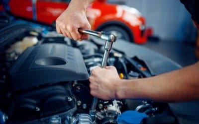 Technician repairing car engine at Big Sky Tire and Repair shop.