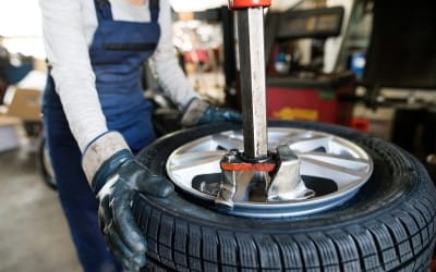 Technician repairing a tire with a hydraulic lift at Big Sky Tire and Repair.