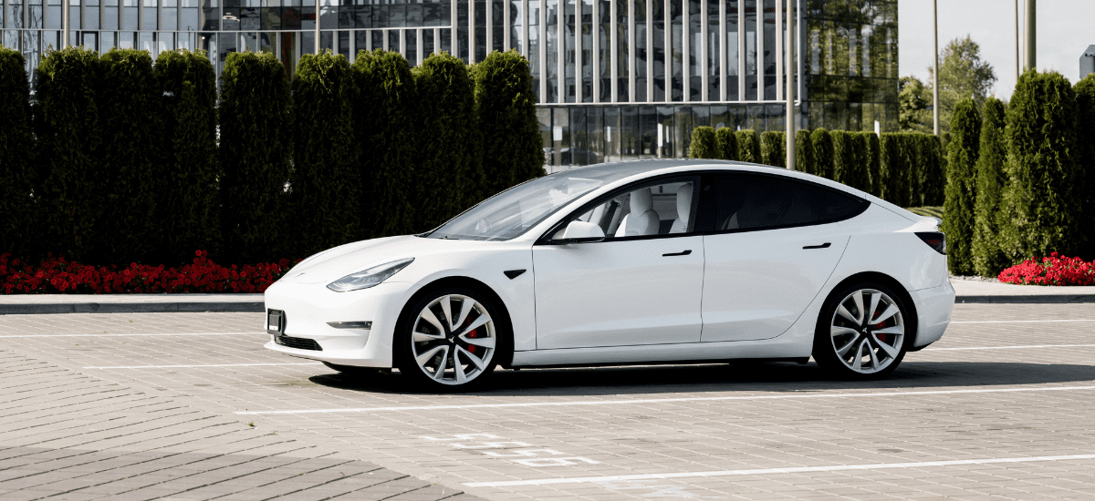 Tesla Model 3 parked outdoors in a sleek, white design with black accents and stylish wheels.
