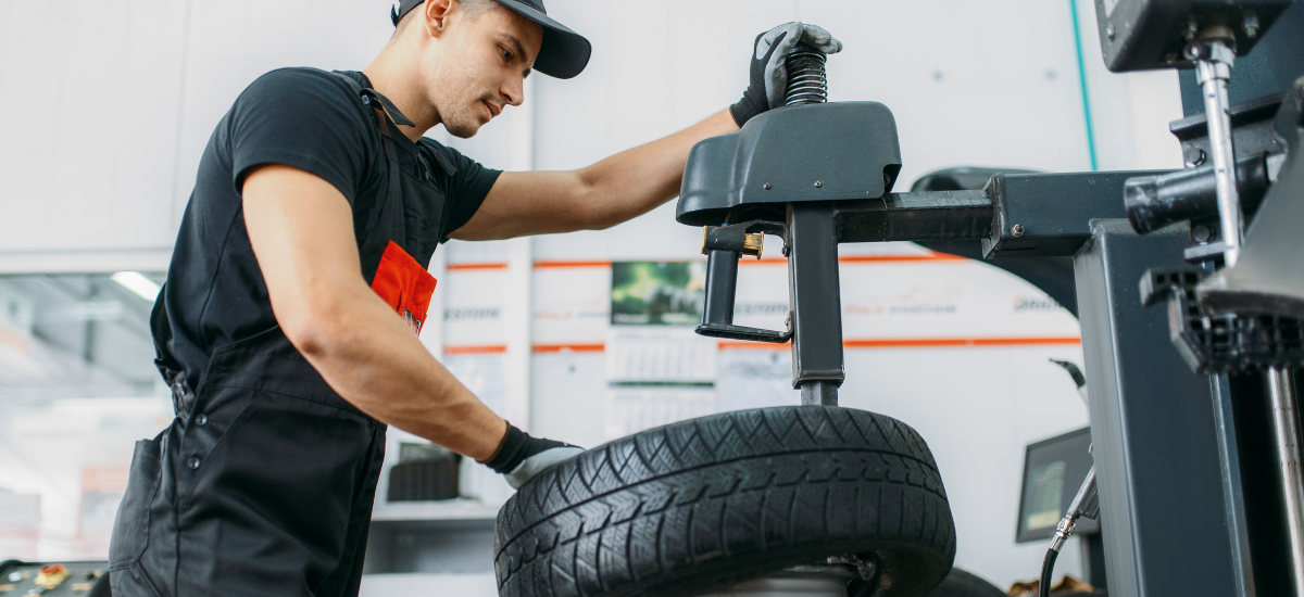 Technician inspecting tire pressure and tread for weather-related wear.